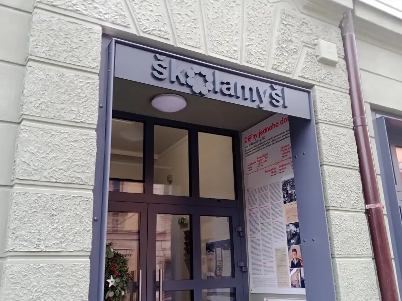 Kovový nápis Školamyšl osazený nad vchodem historické budovy